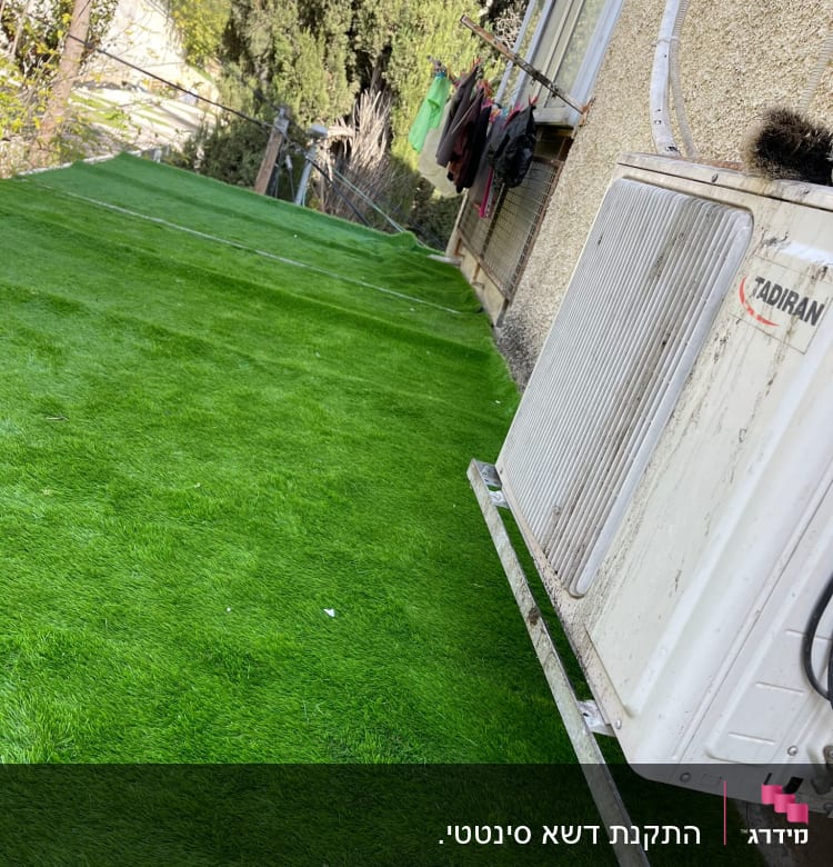 דשא סינתטי ירוק ליד קיר חיצוני של בית